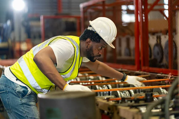 African American industrial worker is checking the setup value of metal sheet roll forming machine inside roof factory for safety industry construction