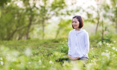 Asyalı kadın, yaz aylarında huzur dolu iç huzur bilgeliğinden mutluluk elde etmek için ormandaki papatya çiçekleri ile dolu ormanda meditasyon yogası yapıyor. Sağlıklı akıl ve ruh için sabah ışığı ile.