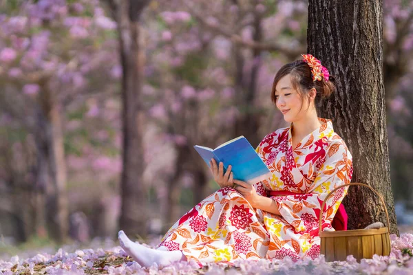 Японская Женщина Традиционном Кимоно Сидя Цветущей Вишней Читая Книгу Время — стоковое фото