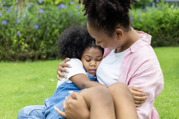 アフリカ系アメリカ人の母親は 幸福と幸福のために公園で夏のピクニック中に庭の芝生で昼寝をしている間に娘を抱き上げています — ストック写真