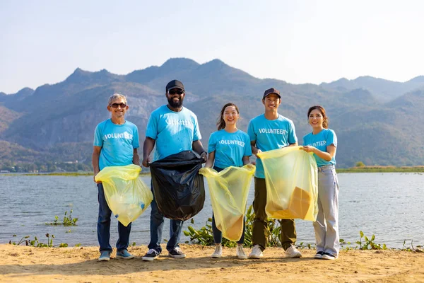 Team of young and diversity volunteer worker group enjoy charitable social work outdoor in cleaning up garbage and waste separation project at the river beach
