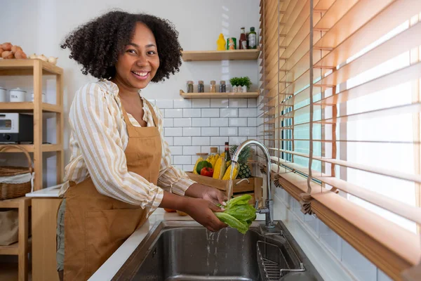 stock image African American housewife is cleaning green lettuce to prepare simple and easy southern style salad meal for vegan and vegetarian food