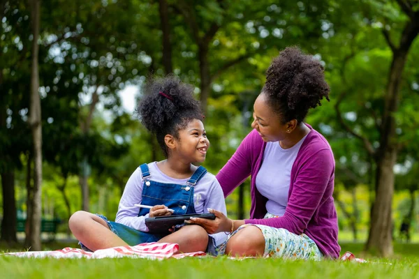 Afroamerykańska Matka Uczy Swoją Młodą Córkę Czytać Pomocą Tabletu Cyfrowego — Zdjęcie stockowe