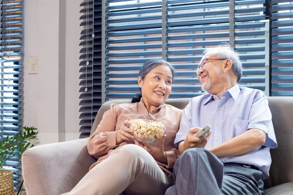 Starsza Azjatycka Para Uśmiecha Się Siedząc Kanapie Bawiąc Się Oglądając — Zdjęcie stockowe