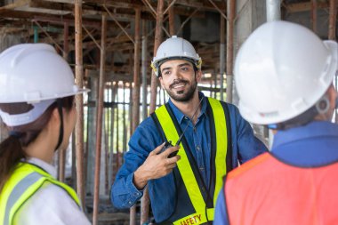 Mühendis, müteahhit ve ustabaşı ekibi inşaat sahasında gayrımenkul geliştirme projesi endüstrisi ve özelleştirme kalite kontrolü için toplantı ve danışmanlık yapıyor.