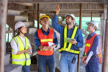Mühendis, mimar, müteahhit ve ustabaşı ekibi inşaat sahasında gayrımenkul geliştirme projesi endüstrisi ve özellik kalite kontrolü için toplantı ve danışmanlık yapıyor.