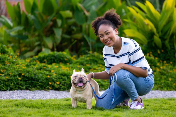 在夏天做完晨练后 非洲裔美国女人一边在草地上的狗狗公园散步 一边和她的法国斗牛犬小狗玩耍 — 图库照片