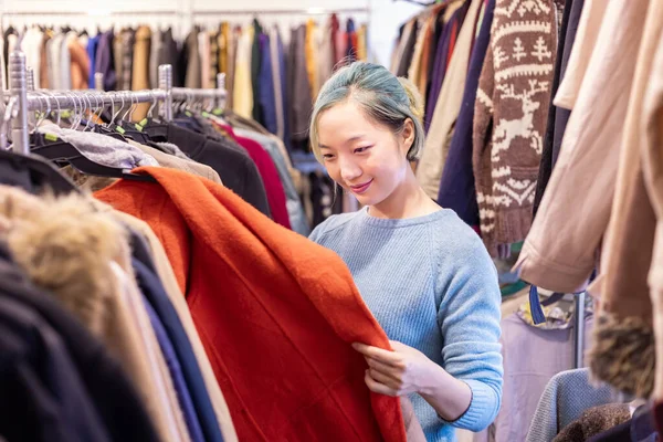 Stylish Asian Woman Choosing Second Hand Sweater Clothing Shop Winter — Stock Photo, Image