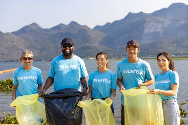 Team of young and diversity volunteer worker group enjoy charitable social work outdoor in cleaning up garbage and waste separation project at river beach