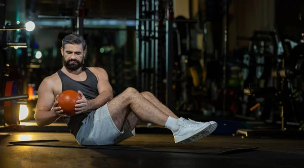 白种人在健身房做坐姿斜扭运动 重药球在地板上 加强腹肌和骨骼肌 — 图库照片