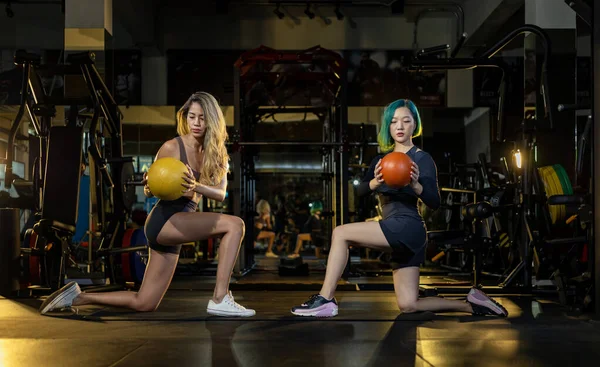两名亚洲女子体操伙伴在地板上做着举重医疗球的扭体运动 加强腹肌和骨骼肌的力量 — 图库照片
