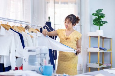 Moda tasarımcısı, moda tasarımı ve giyim sektörü için atölye atölyesinde çalışırken yeni tasarım gömleğini mezurayla ölçüyor.