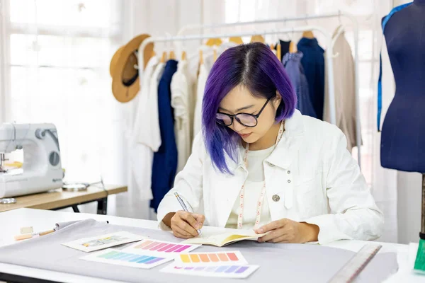 Fashionable freelance dressmaker is designing on new dress by drawing illustrator while working in artistic workshop studio for fashion design and clothing business industry