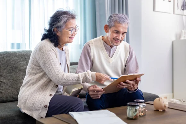 Senior Asian couple is planning on retirement saving fund looking at their income and expense and annual pension after taxes for elder long term financial investment and budget