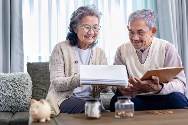 Senior Asian couple is planning on retirement saving fund looking at their income and expense and annual pension after taxes for elder long term financial investment and budget