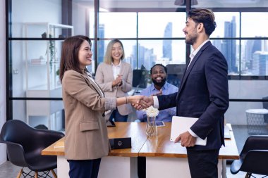 Beyaz iş adamlarının lideri, modern ofis işyerinde gökdelen manzaralı bir şekilde el sıkıştığı için takım arkadaşını tebrik ediyor.