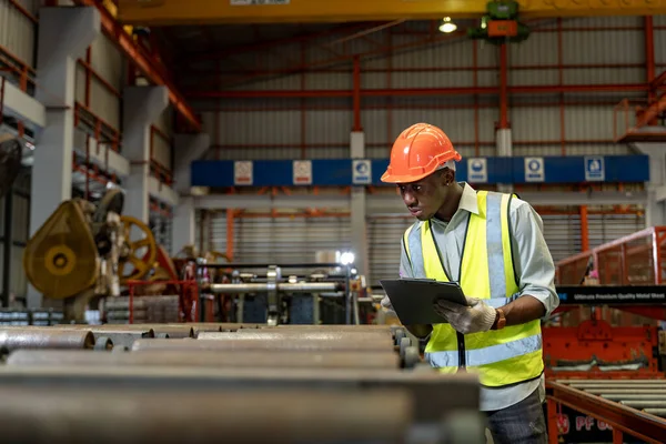 Afrikalı Amerikalı endüstriyel işçiler, güvenlik endüstrisi inşaatı için çatıdaki metal levha oluşturma makinesinin kurulum değerini kontrol ediyorlar.