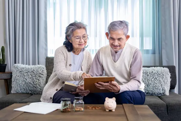 Senior Asian couple is planning on retirement saving fund looking at the income and expense and annual pension after taxes for elder long term financial investment and budget