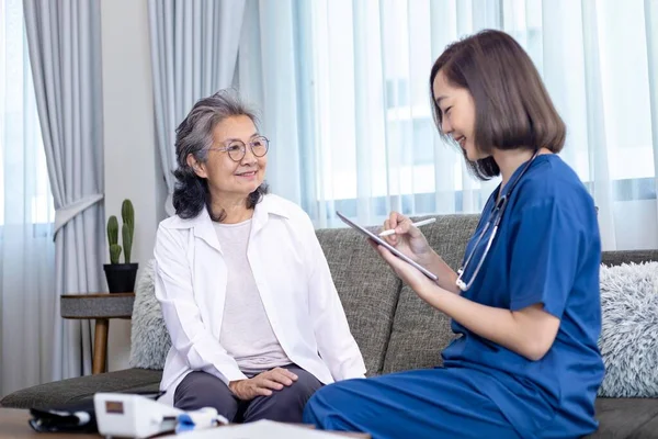 Senior woman got medical service visit from caregiver nurse at home while having result of medical exam for health care and pension welfare insurance