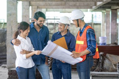 Yeni evli çift inşaat alanındaki müteahhitleriyle ev sahipliği ve gayrimenkul geliştirme çalışmalarının gelişimi ve kalite kontrolü için görüşüyor.