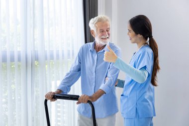 Bakımevi hemşiresi, emeklilik merkezinde koşu bandı kullanarak tedavi sonrası rehabilitasyon ve iyileşme sürecinde beyaz adamı destekliyor.