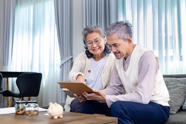Senior Asian couple are planning on retirement saving fund looking at their income and expense and annual pension after taxes for elder long term financial investment and budget
