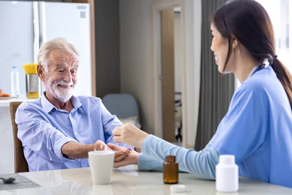 Senior caucasian man got medical service visit from caregiver nurse at home while explaining on doses of vitamins and drug pill for health care and pension welfare insurance