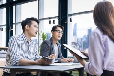 Genç Asyalı girişimci takımının pazarlama ve satış yönetimi için küçük bir takım toplantısı var. Girişim ve eğitim kullanımı için gökdelen görünümlü bir proje.