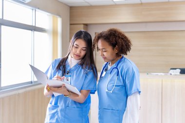 Çeşitlilik doktoru ve hemşire, deneyimli bir hekim uzmanıyla, tam bakım planı üzerine, hastanın tıbbi kayıtlarını tartışıyor ve beyin fırtınası yapıyor.