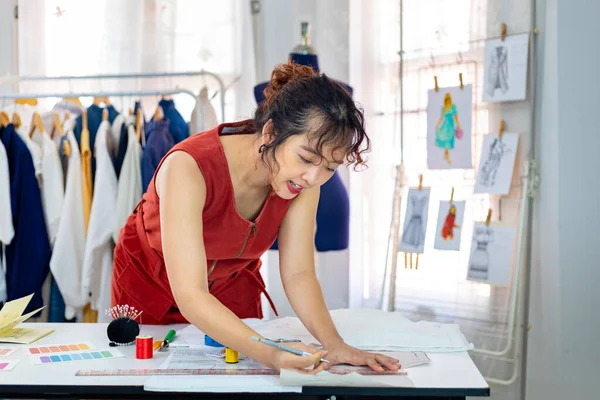 ドレスメーカーは ファッションデザインと衣料品ビジネス業界のための芸術的なワークショップスタジオで働いている間 新しいカスタムメイドドドレスのためのムスリンの調整を行っています — ストック写真
