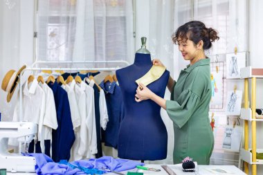 Moda tasarımcısı, moda tasarımı ve giyim sektörü için atölyesinde çalışırken mankene iğneleyerek yeni elbise için marka tasmasını takıyor.