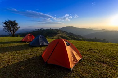 Bir grup maceraperest çadırı, gece kamp alanı boyunca Mae Tho, Chiangmai, Tayland 'ın manzaralı güzel günbatımı manzarasında açık hava macera seyahati için dağların tepesinde.