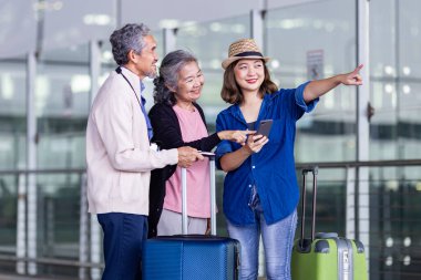 Bir grup Asyalı aile turist, tatil ve uzun hafta sonu tatili süresince havaalanından taksi çağırmak için mobil başvuru kullanıyor.