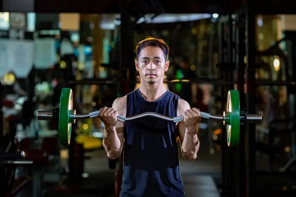 アジアの筋肉の男は運動およびトレーニングのための暗い背景が付いている体育館の内側の棒そして中心の筋肉の初心者として容易な棒を使用して練習重量のライフをしています — ストック写真