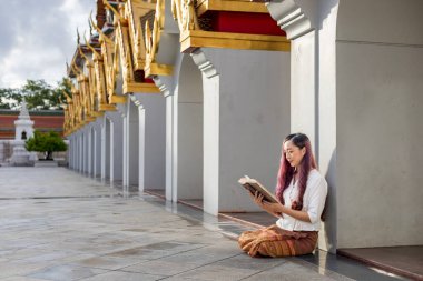 Asyalı Budist kadın Sanskritçe antik Tripitaka kitabı okuyor. Lord Buddha Dhamma, tapınakta oturup manastırda ilahiler okuyup ibadet ederken.