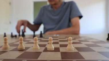 İnsanlar evlerinde satranç oynuyorlar ve oyun konsepti üzerinde strateji planlaması ve eleştirel düşünme için tahtayı taşlarla hazırlıyorlar.