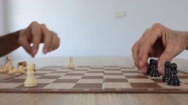 İnsanlar evlerinde satranç oynuyorlar ve oyun konsepti üzerinde strateji planlaması ve eleştirel düşünme için tahtayı taşlarla hazırlıyorlar.