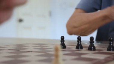 İnsanlar evlerinde satranç oynuyorlar ve oyun konsepti üzerinde strateji planlaması ve eleştirel düşünme için tahtayı taşlarla hazırlıyorlar.
