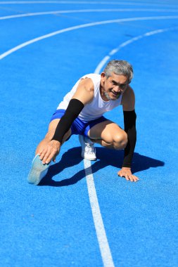 Kıdemli Asyalı atlet profesyonel egzersiz, spor antrenmanı ve uzun yaşam için sağlıklı olan profesyonel mavi pistte koşmak için ısınma hareketleri yapıyor.