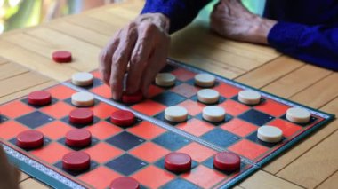 Kıdemli Asyalı baba ve oğlu, boş zamanlarında evde dama oynamaktan ve Alzheimer semptomlarını önlemekten zevk alıyorlar.