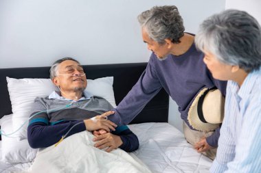 Ölümcül oksijen maskeli yaşlı erkek hasta, evinde son evre kanserden palyatif tıbbi tedaviyle acı çekerken, arkadaşı ve ailesinden teselli buluyor.