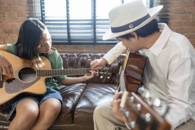Genç Asyalı kız, okul sonrası müzik dersinde öğretmeninden gitar çalmayı öğreniyor. Çocukların yetenek ve yetenek geliştirme konsepti.