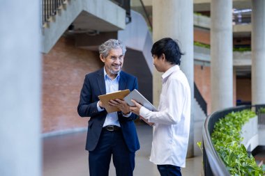 Üniversitede eğitim, akademik ve iş konsepti fakültesinde otururken, Asyalı son sınıf profesörü üniversite öğrencilerine araştırma tezi hakkında tavsiyelerde bulunuyor.