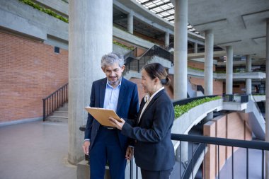 Asyalı üst düzey yönetici, uluslararası iş genişletme ve küresel başarı konsepti için sekreterinden yeni pazarlama stratejisi yatırım planına bakıyor