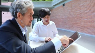Üniversitede eğitim, akademik ve iş konsepti fakültesinde otururken, Asyalı son sınıf profesörü üniversite öğrencilerine araştırma tezi hakkında tavsiyelerde bulunuyor.