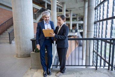 Asyalı üst düzey yönetici, uluslararası iş genişletme ve küresel başarı konsepti için sekreterinden yeni pazarlama stratejisi yatırım planına bakıyor