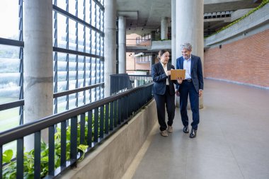 Asyalı üst düzey yönetici, uluslararası iş genişletme ve küresel başarı konsepti için sekreterinden yeni pazarlama stratejisi yatırım planına bakıyor