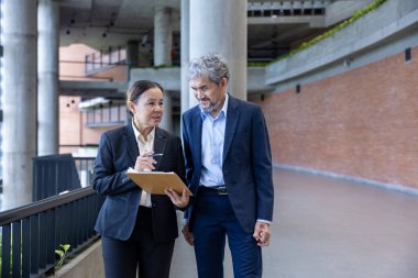 Asyalı üst düzey yönetici, uluslararası iş genişletme ve küresel başarı konsepti için sekreterinden yeni pazarlama stratejisi yatırım planına bakıyor