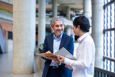 Üniversitede eğitim, akademik ve iş konsepti fakültesinde otururken, Asyalı son sınıf profesörü üniversite öğrencilerine araştırma tezi hakkında tavsiyelerde bulunuyor.