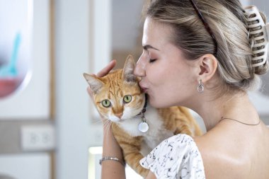 Kedi sahibi, kızıl kedisini bakıcısının yatılı servisi ve hayat boyu yoldaşı olan arkadaşı için barınaktan kurtardıktan sonra sevgiyle öpüyor ve sarılıyor.